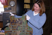Photo: Carrie Cutchens at work on the exhibit. Photo courtesy of Spc. Nicole Kojetin.