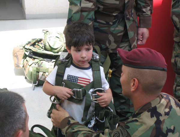Photo: A 82d Airborne Division paratrooper rigs a parachute on a young visitor at the museum's 