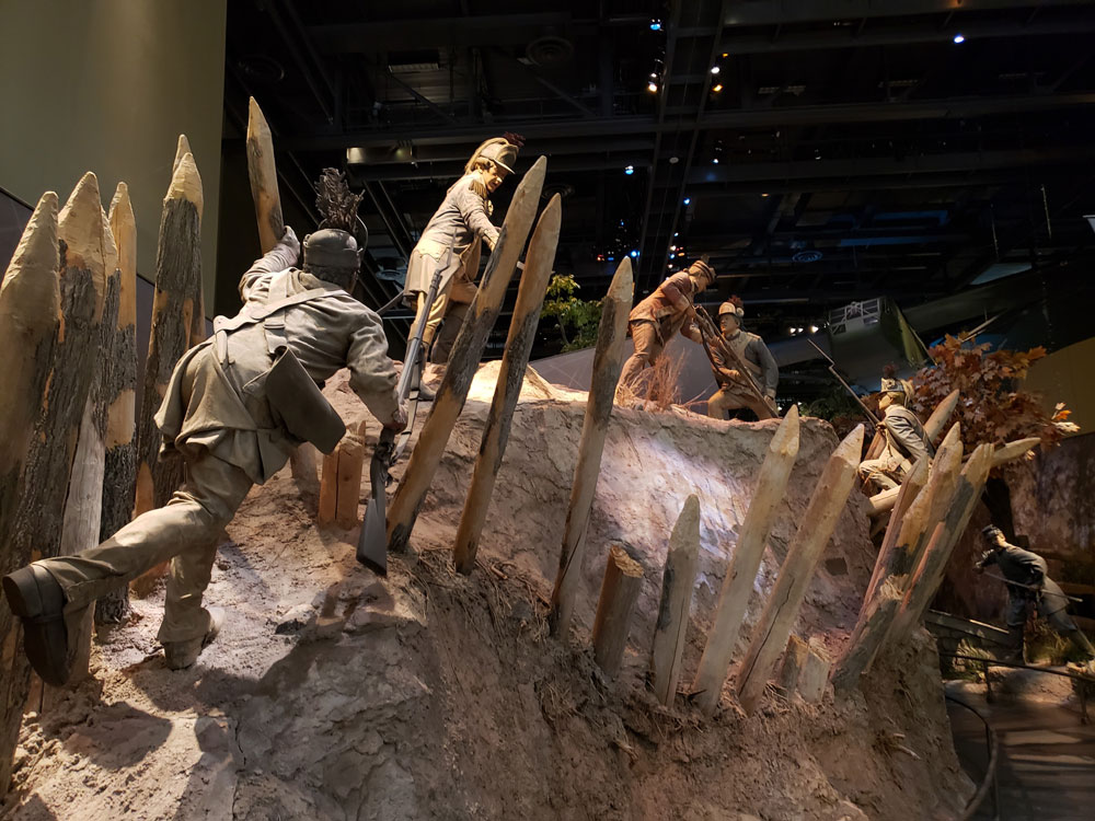 Museum display of several Soldiers trekking on a mountainside.