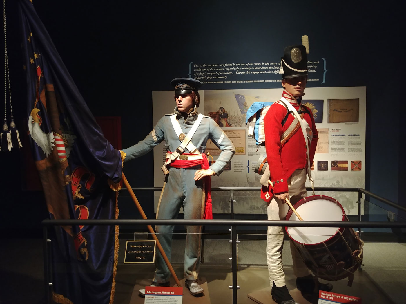 Museum display of one Soldier holding flag and one Soldier holding drum.