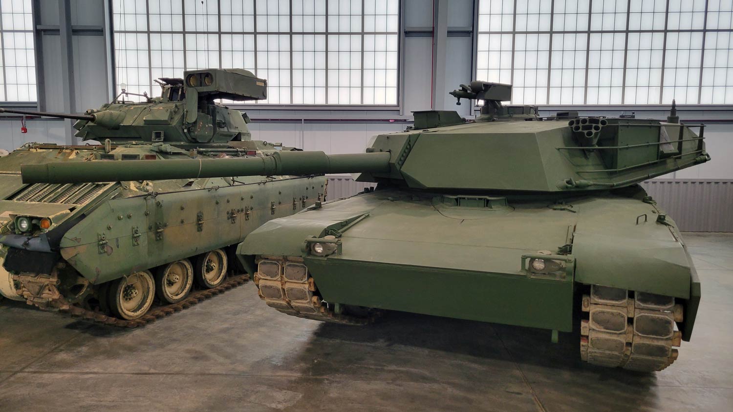 Two US Army AFV's on display in hangar.