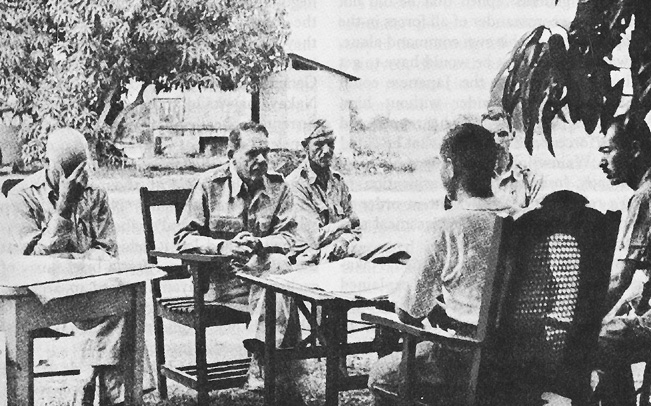 Photo:  Discussing surrender terms with Colonel Nakayama.  Facing forward, left to right, Col. Everett C. Williams, Maj. Gen. Edward P. King, Jr., Maj. Wade Cothran, and Maj. Achille C. Tisdelle