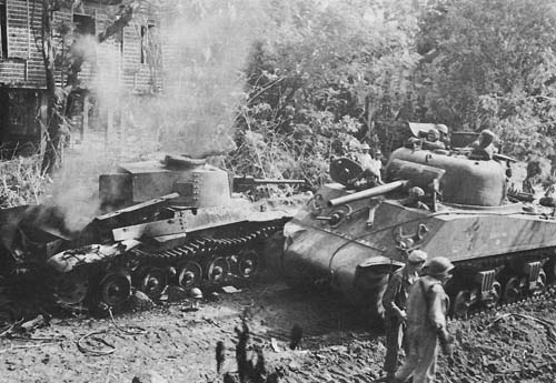 Photo:  Sherman tank passing a burning Japanese medium tank, Luzon