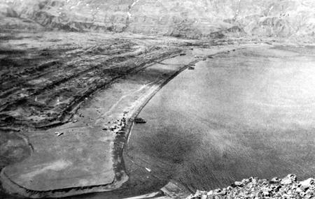 Photo: ATTU LANDINGS. The west arm of Holtz Bay viewed from the ridge over which the troops advanced. Note crashed Japanese Zero.