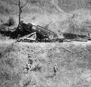 Japanese truck and tankette trapped by crater blown in the Burma Road by MARS demolition men.