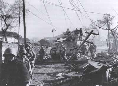 U.S. soldiers with tank make their way through the rubble-strewn streets of Hyesanjin in November 1950.