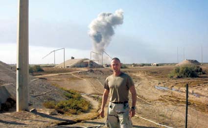 Sgt. Enea Cutuca. In the background is a controlled explosion of about 10,000 pounds of ordnance we had collected over time.