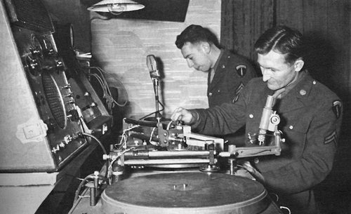 Photo:  Technicians operate a record player during an overseas broadcast