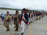 Photo:  Reenactors commemorate the arrival of the Lewis and Clark Expedition in St. Louis in ceremonies on the west bank of the Mississippi. The “civilian” (in the center) portrays George Drouillard. 