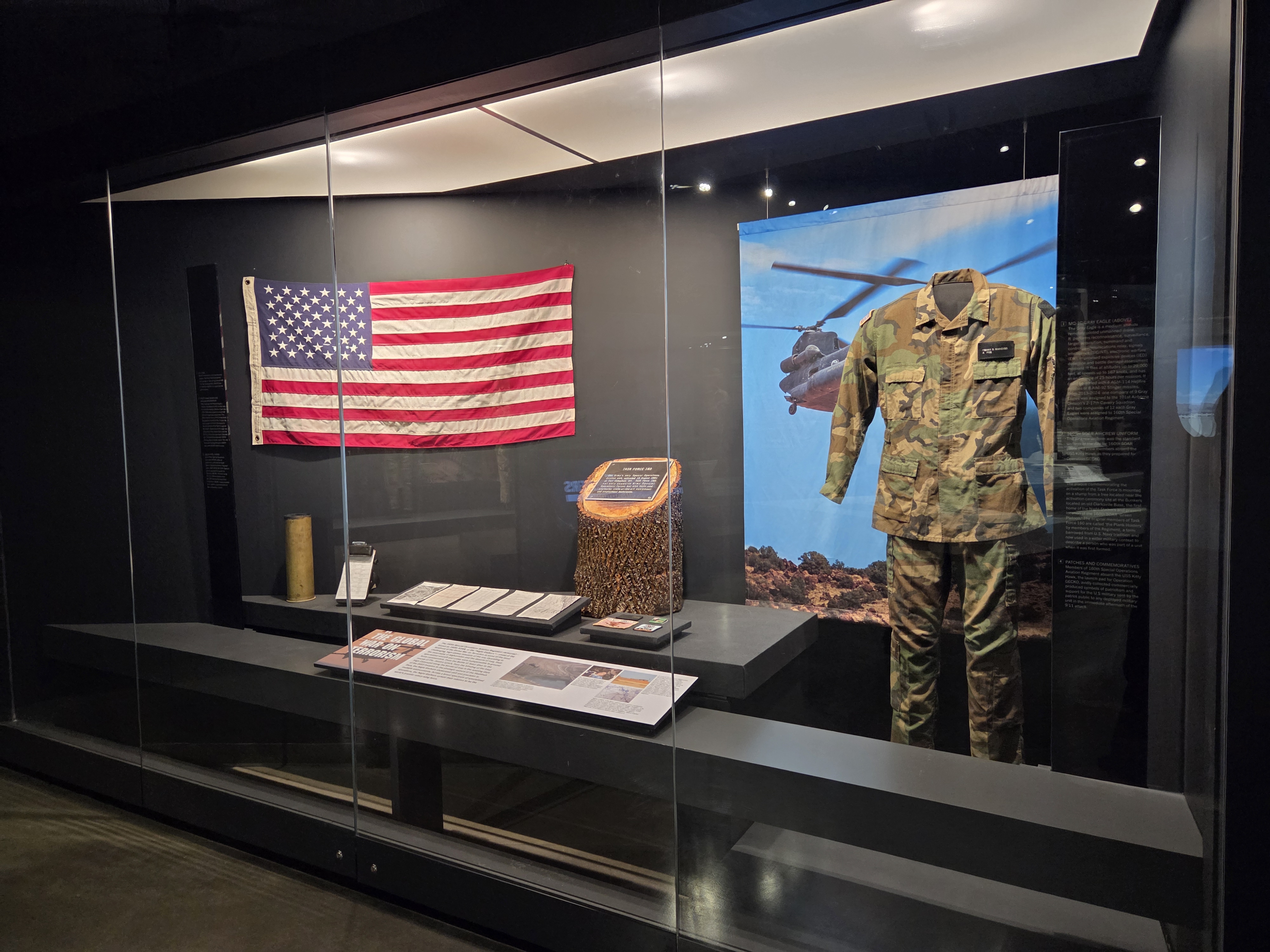 Display case featuring modern U.S. Army uniforms, an American flag, and artifacts from the Global War on Terrorism.