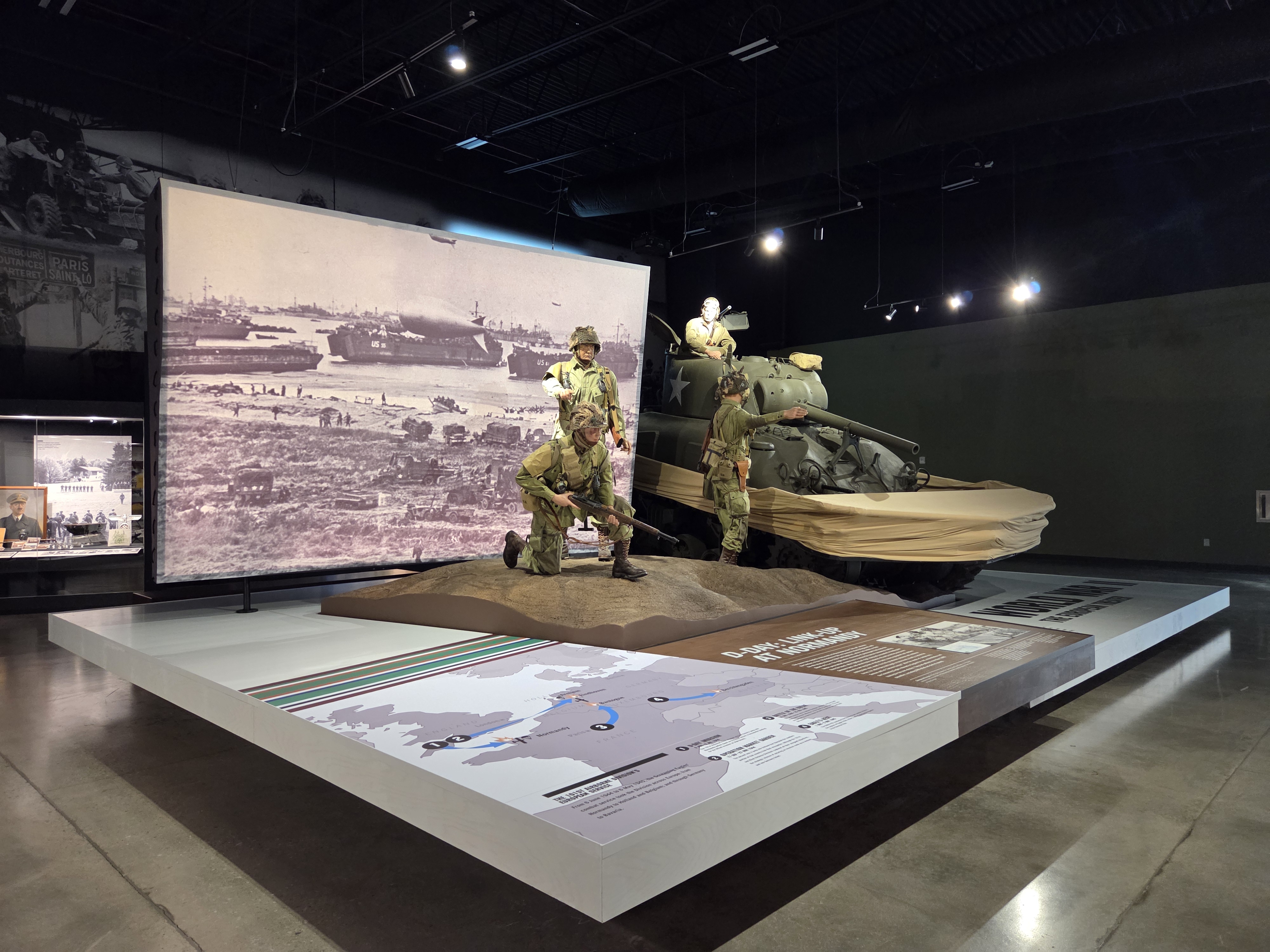 Large D-Day exhibit with soldier figures, landing craft imagery, and a Sherman tank inside the Tennessee Wings of Liberty Museum.